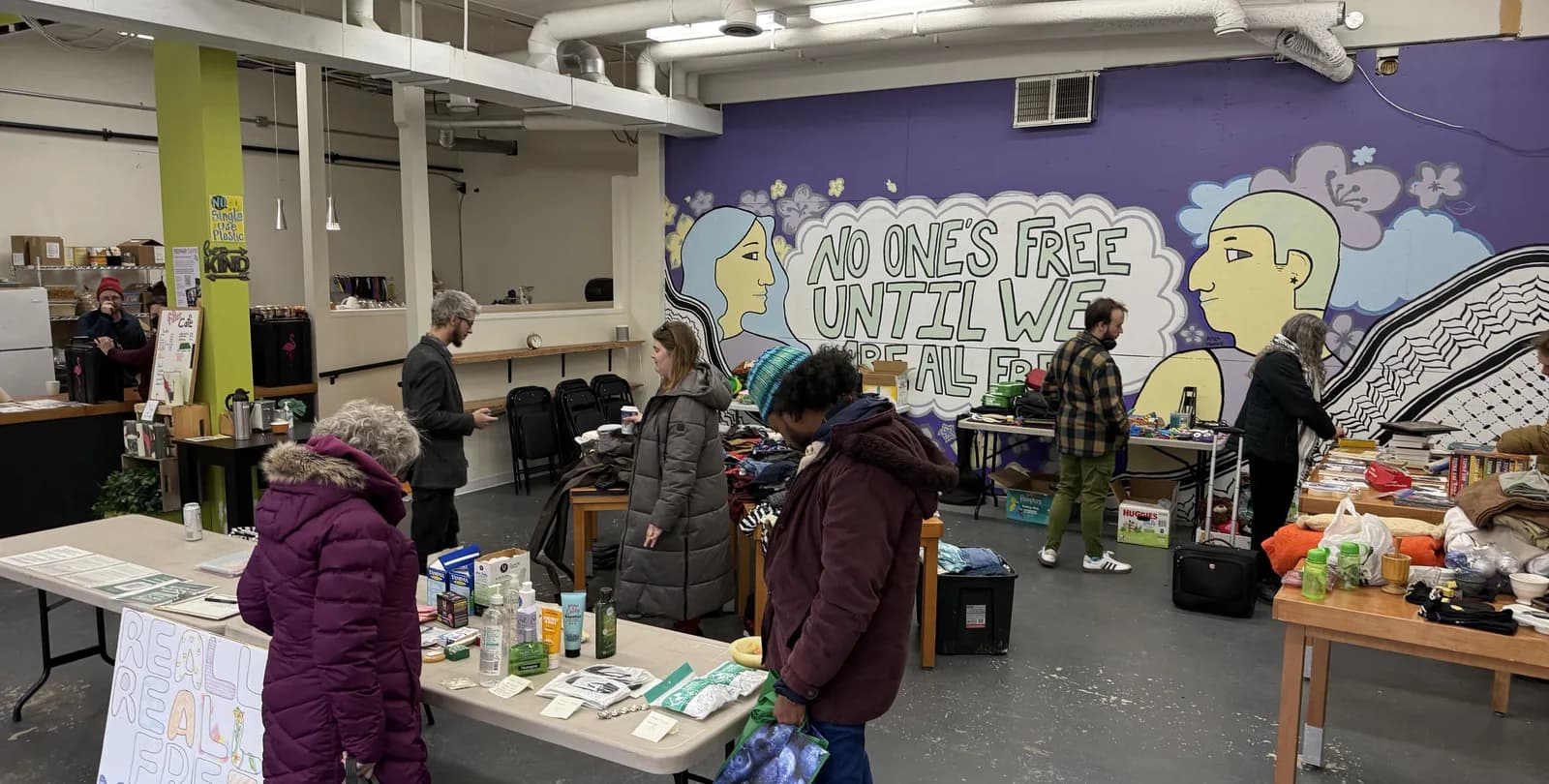 A swap at 206 Piccadilly: long tables covered in clothes, books and household things, with people in winter coats looking through them